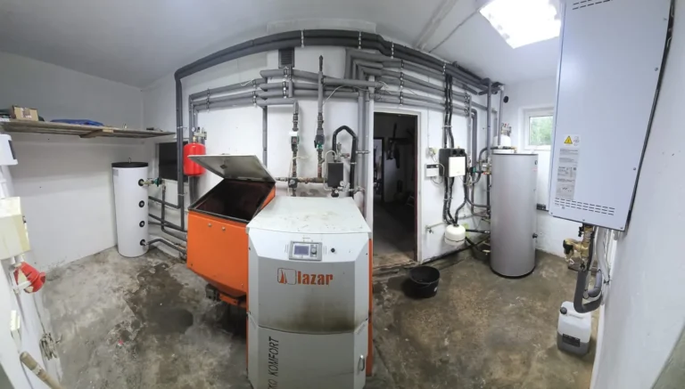 Widok kotłowni z pompą ciepła, kotłem i instalacją rurową w Wilczy